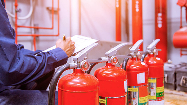 Trabajador realizando inspección del estado de extintores. BSTR - Basic Safety Training Refresh.