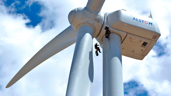 Fotografía de la nacelle de un aerogenerador del que están colgando dos técnicos realizando trabajos en altura en un parque eólico