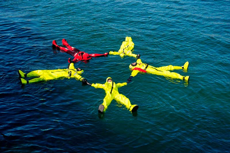 fotografía de alumnos de Total HSE realizando prácticas reales en el mar de la formación BST de GWO, en específico del módulo de Supervivencia en el mar (Sea Survival), con trajes de inmersión.
